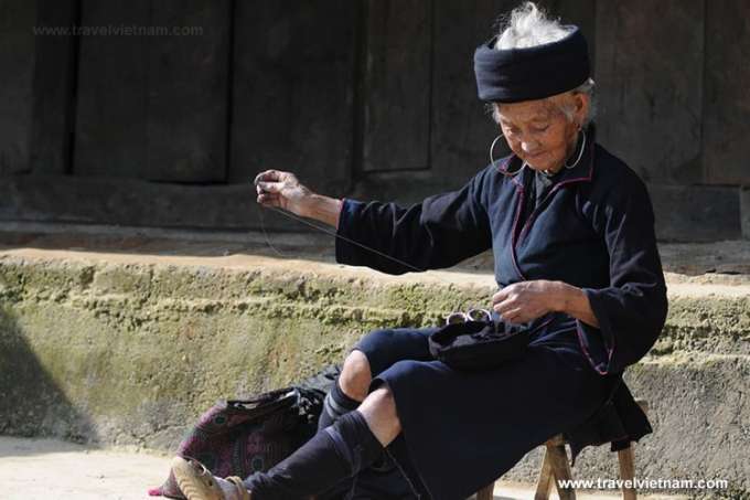 An old woman sewing in the courtyard