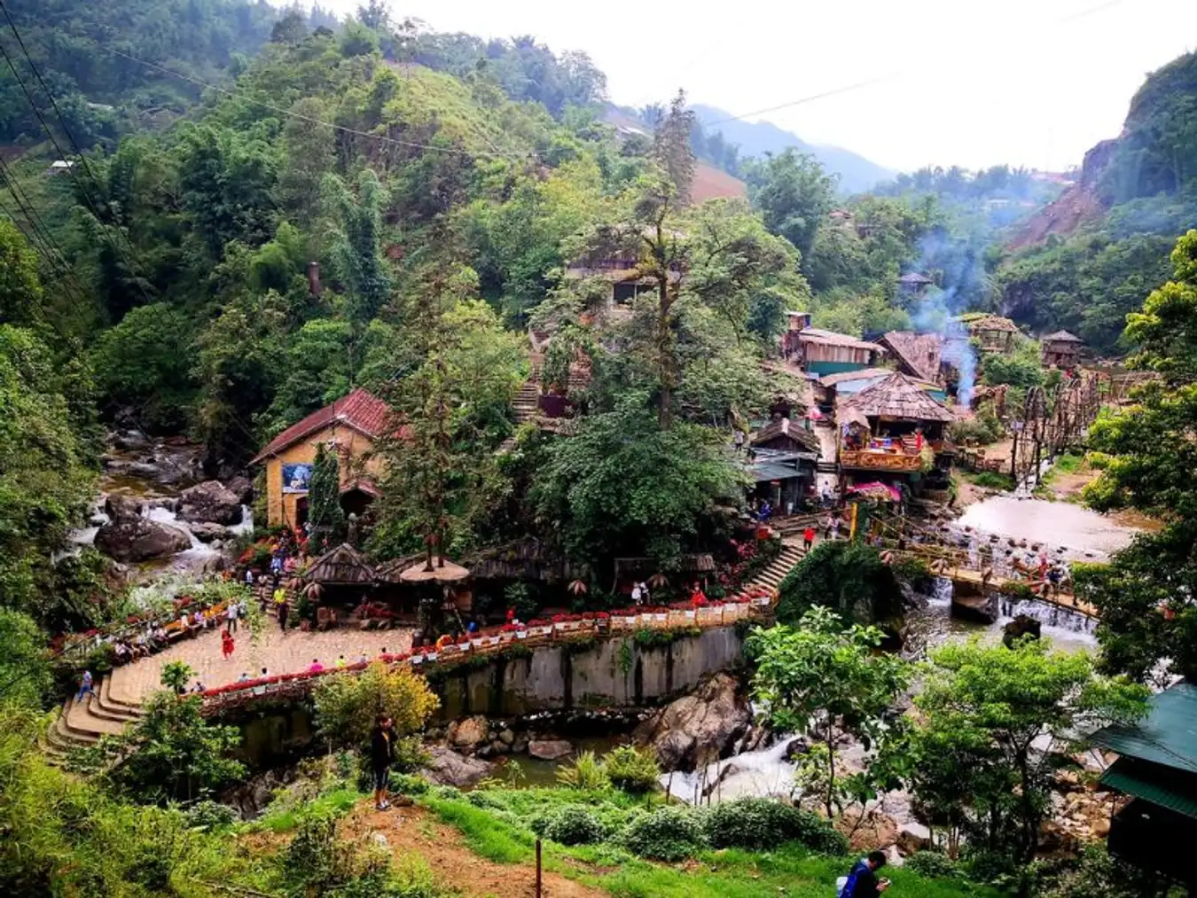 A panoramic view of Cat Cat Village nestled in the lush green hills, showcasing traditional houses 